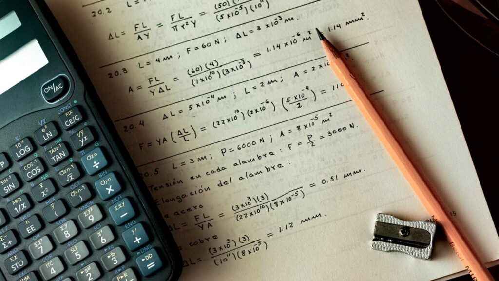 Fotografie eines Taschenrechners und einer mathematischen Formelsammlung auf Papier.